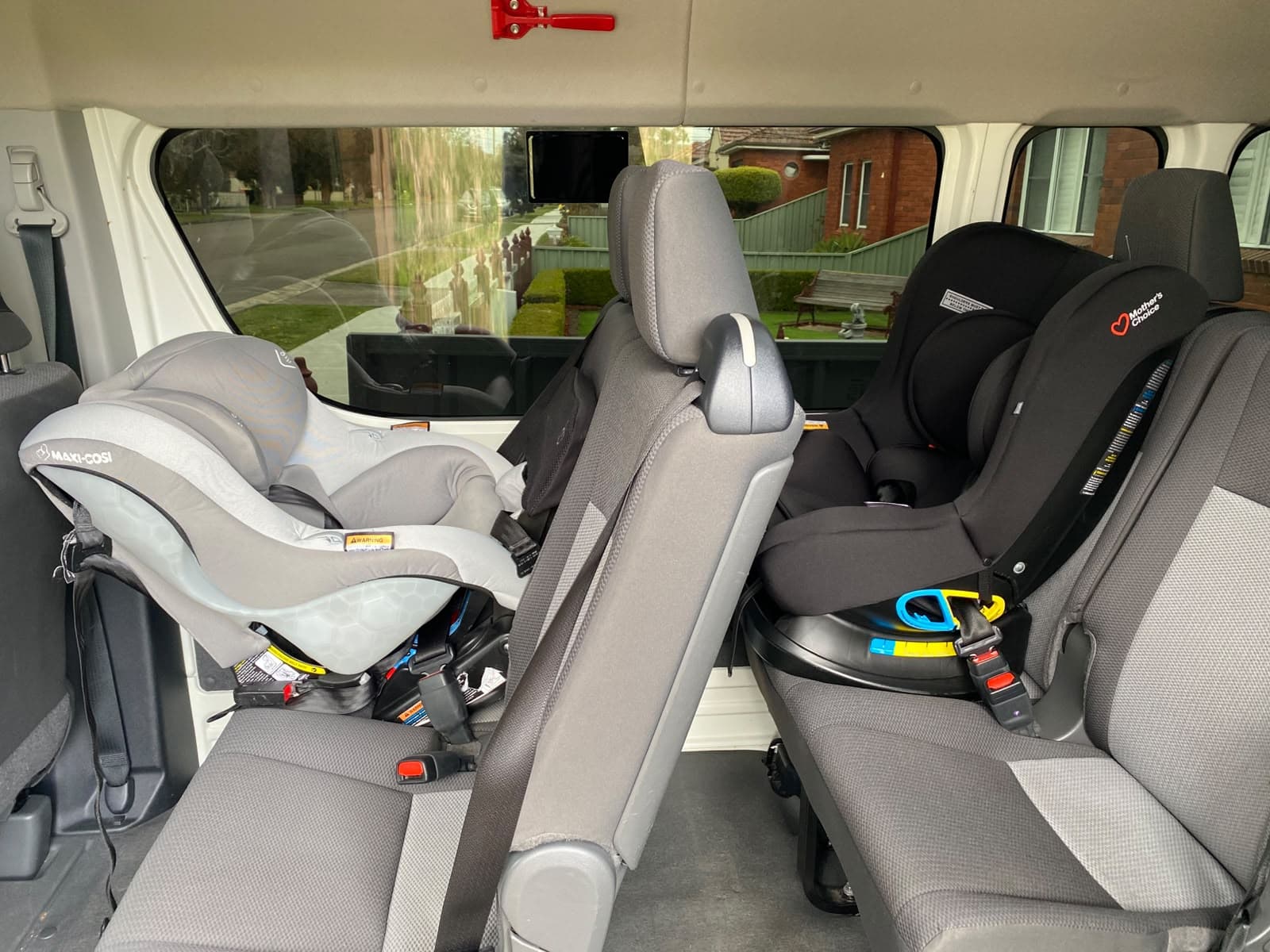 Two rear-facing baby seats fitted side by side in our van - a grey infant capsule and a black rotating baby seat, both in place before pickup