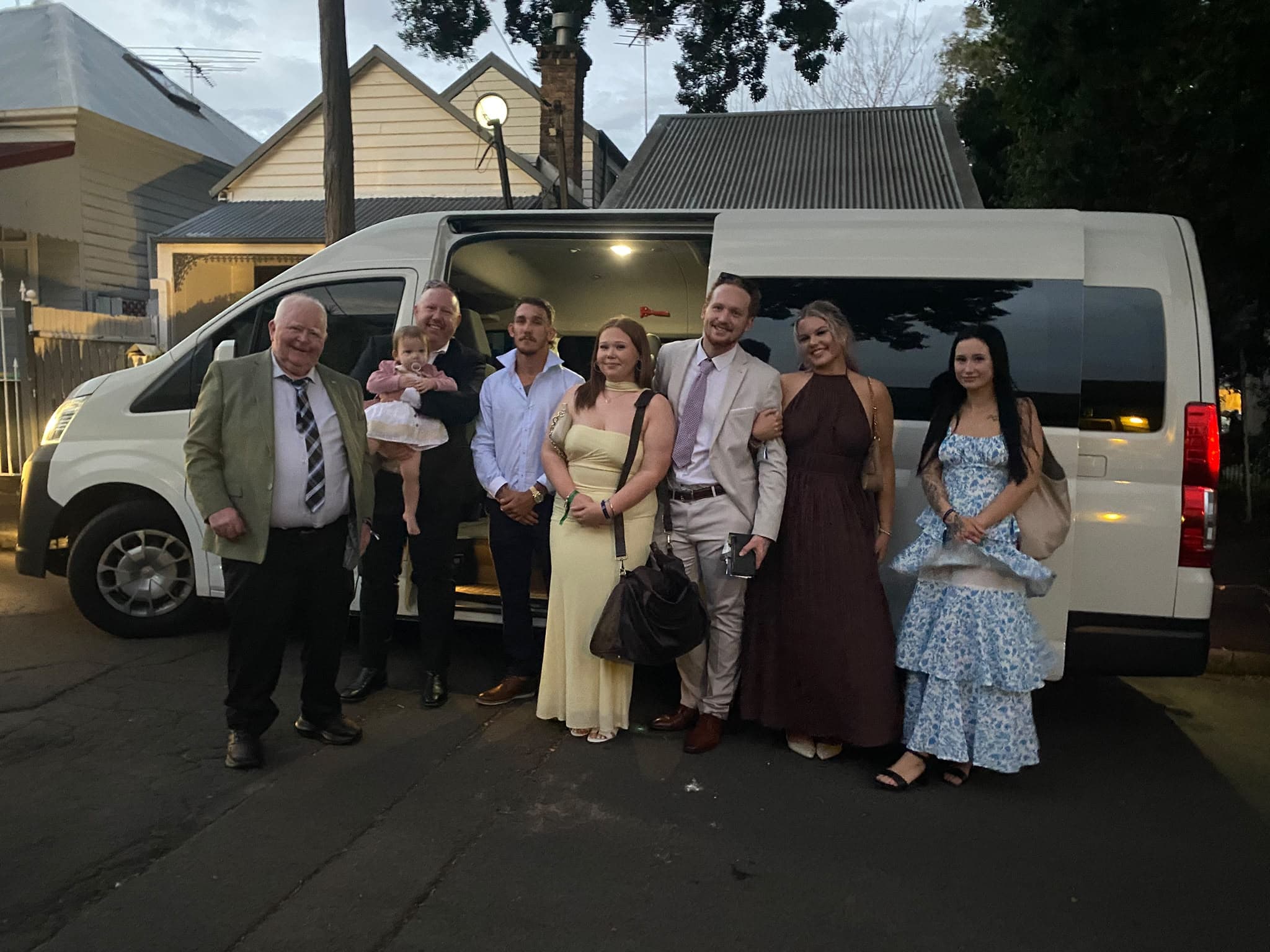 Three generations of one family, from a baby in arms to grandparents, standing together in front of our van before setting off
